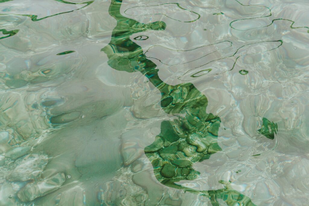 Calm water surface with abstract green reflections and light patterns.